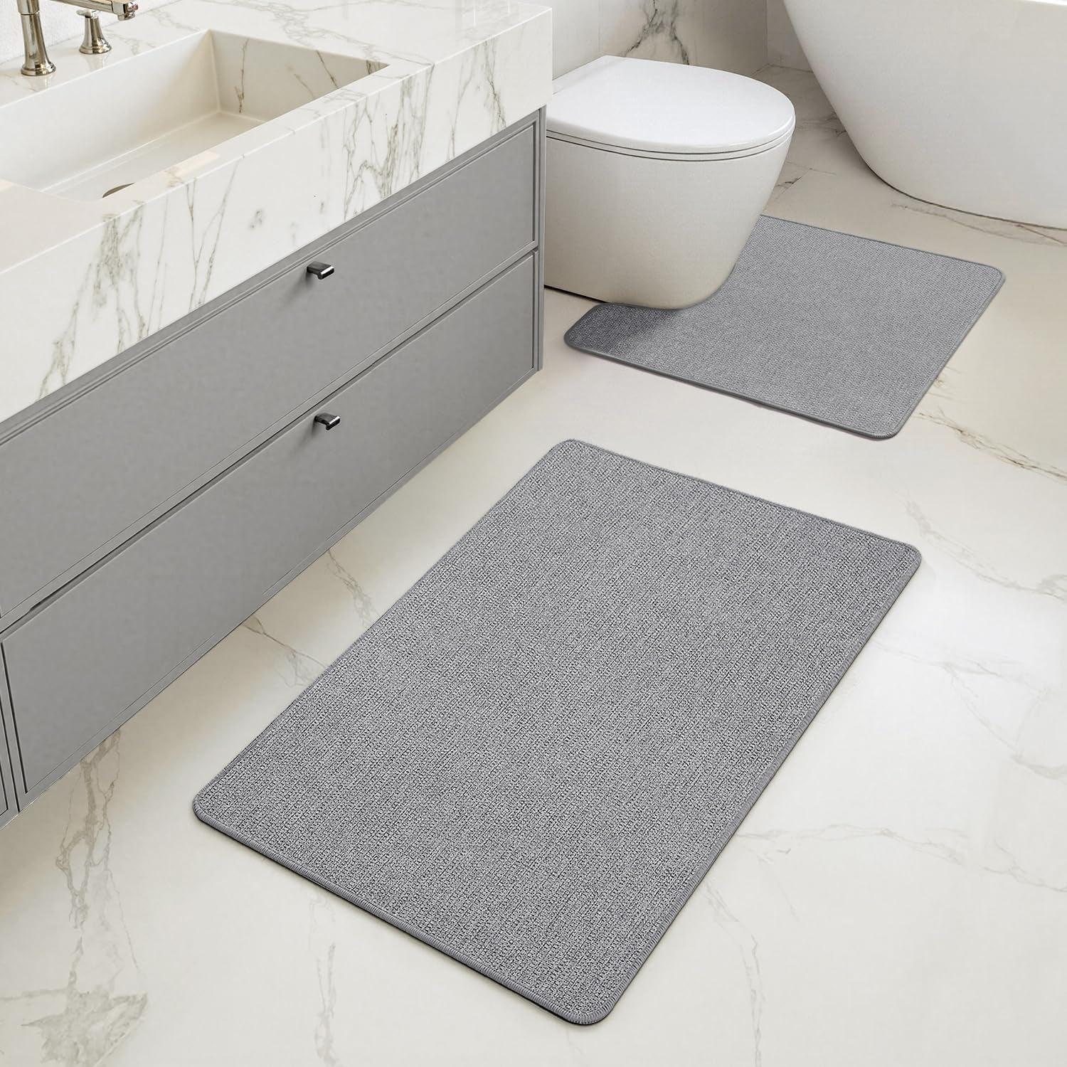 View of bathroom vanity and toilet with matching light-gray rectangular rugs, one U-shaped by the toilet