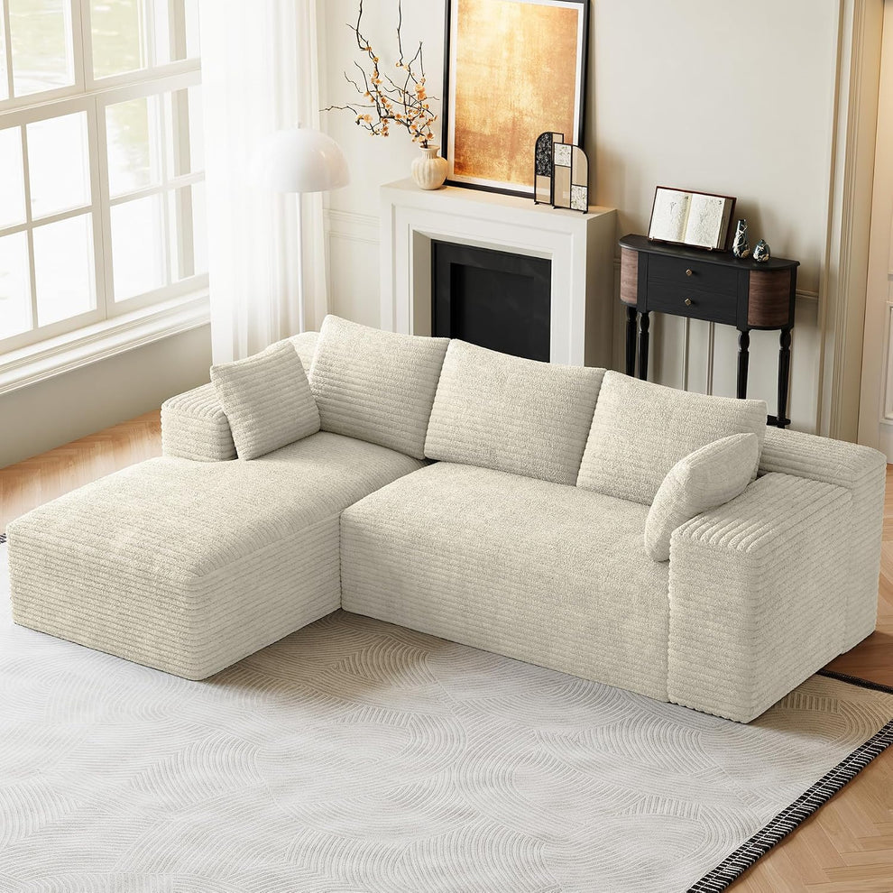 Cream-colored L-shaped modular sectional with chaise in a bright living room beside a fireplace and window.