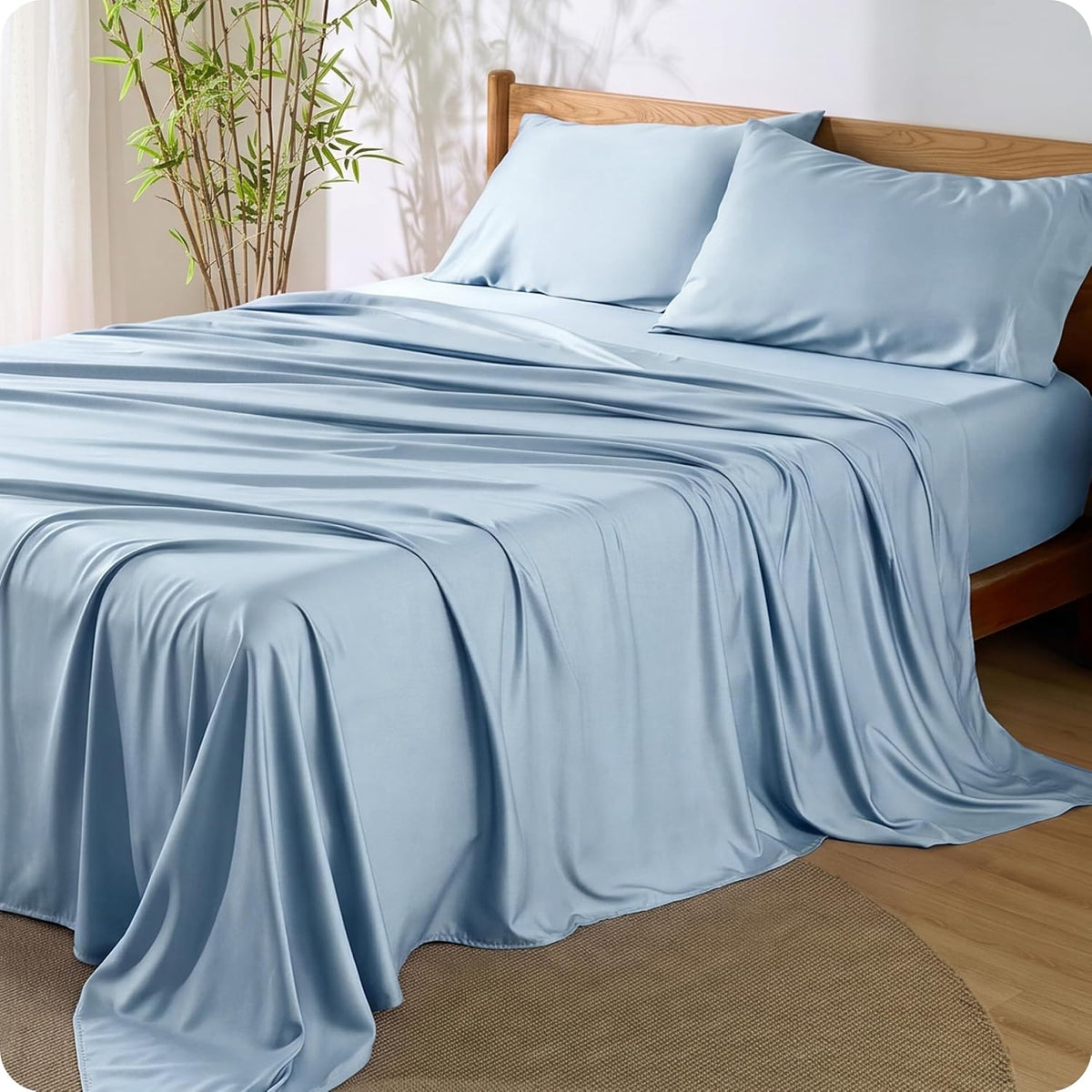 Light blue sheets draped over a bed with matching pillowcases and a wooden headboard.