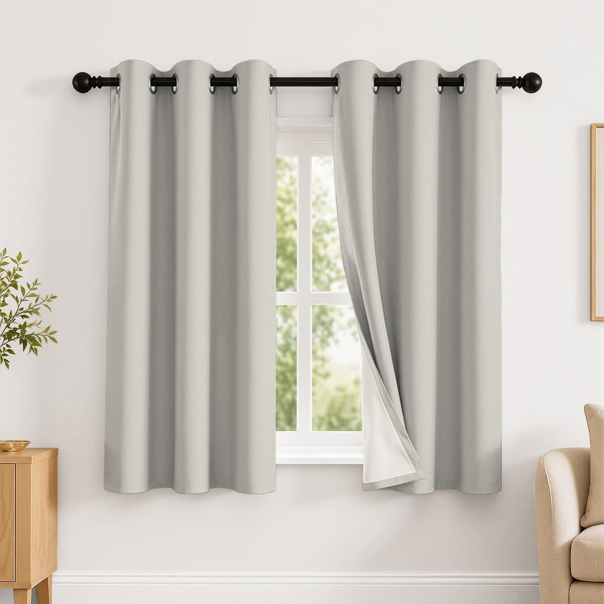Short light gray grommet curtains with one panel slightly pulled back showing white backing.