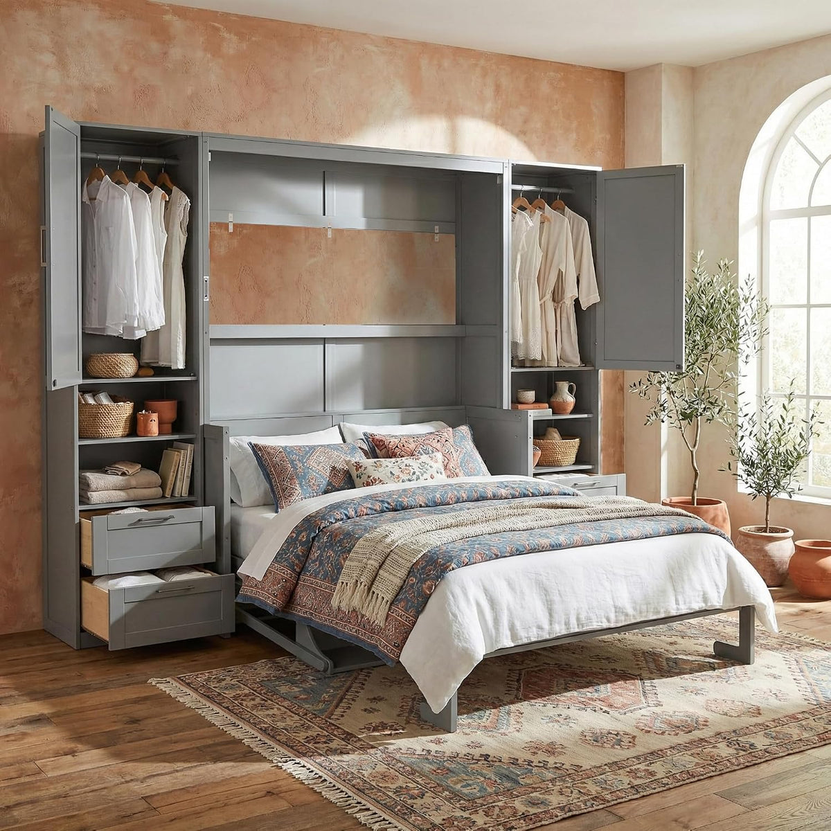 Gray wall bed pulled down with open side cabinets, patterned bedding, rug and potted plants by window