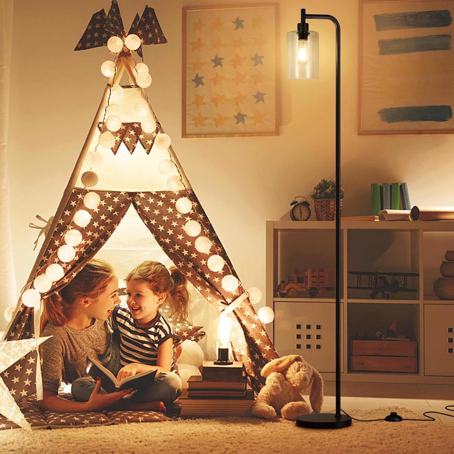 Black floor lamp with clear glass shade illuminating a children's play tent in a room