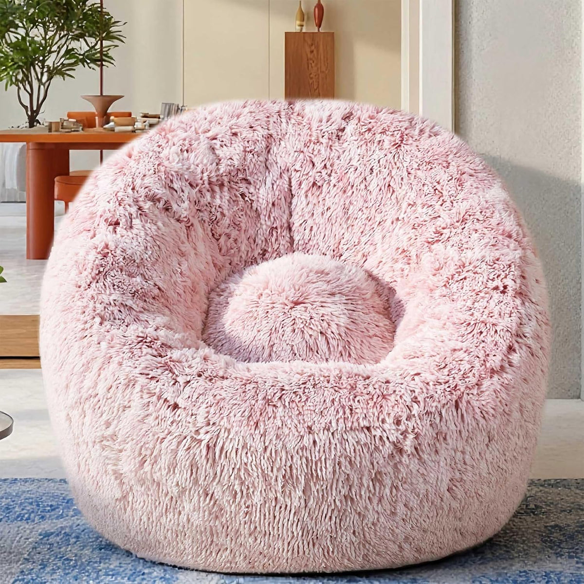 Front-facing pink plush U-shaped bean bag chair placed on a rug in a modern room
