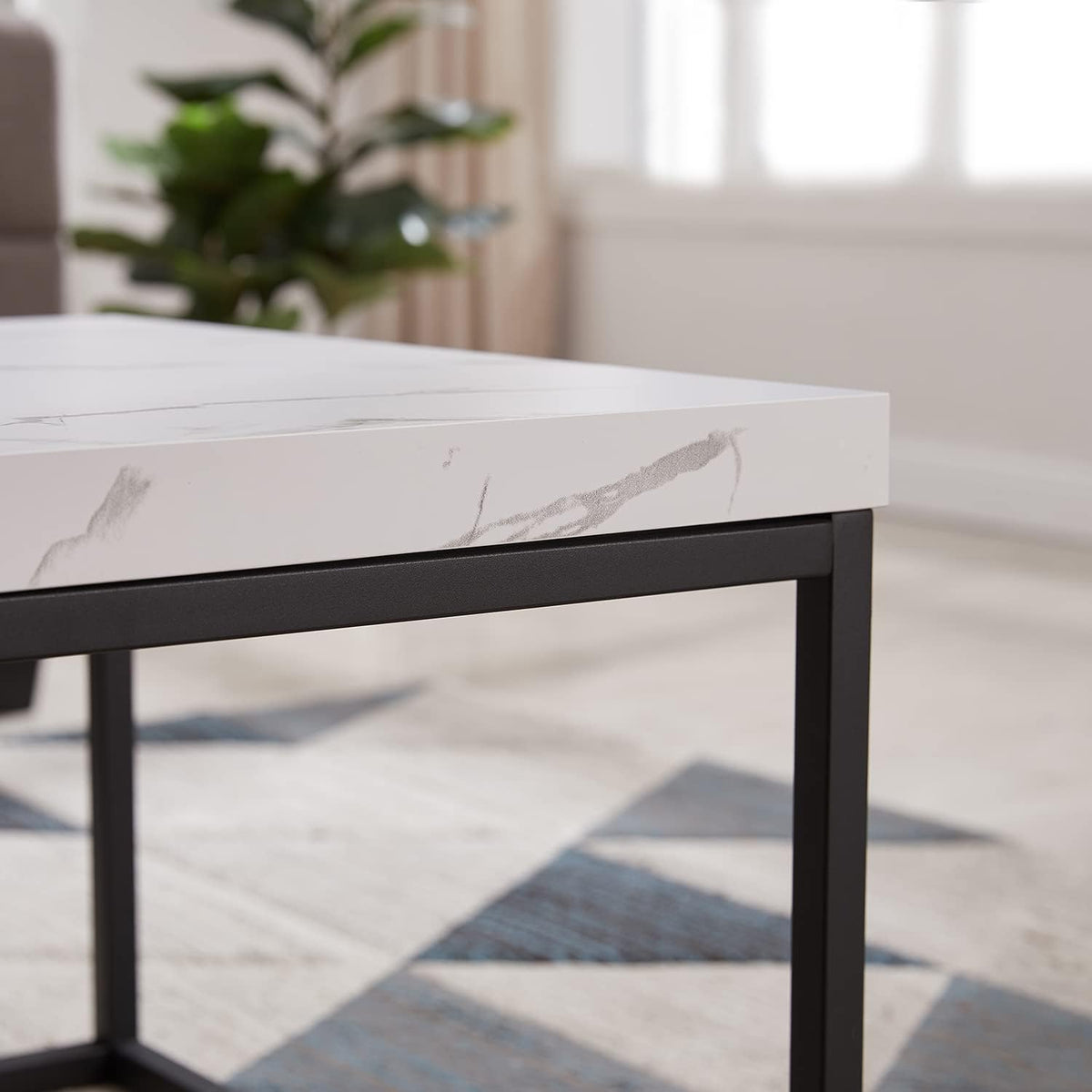 Close-up of the table corner showing marble-look veining on the thick top and the matte black metal frame beneath.