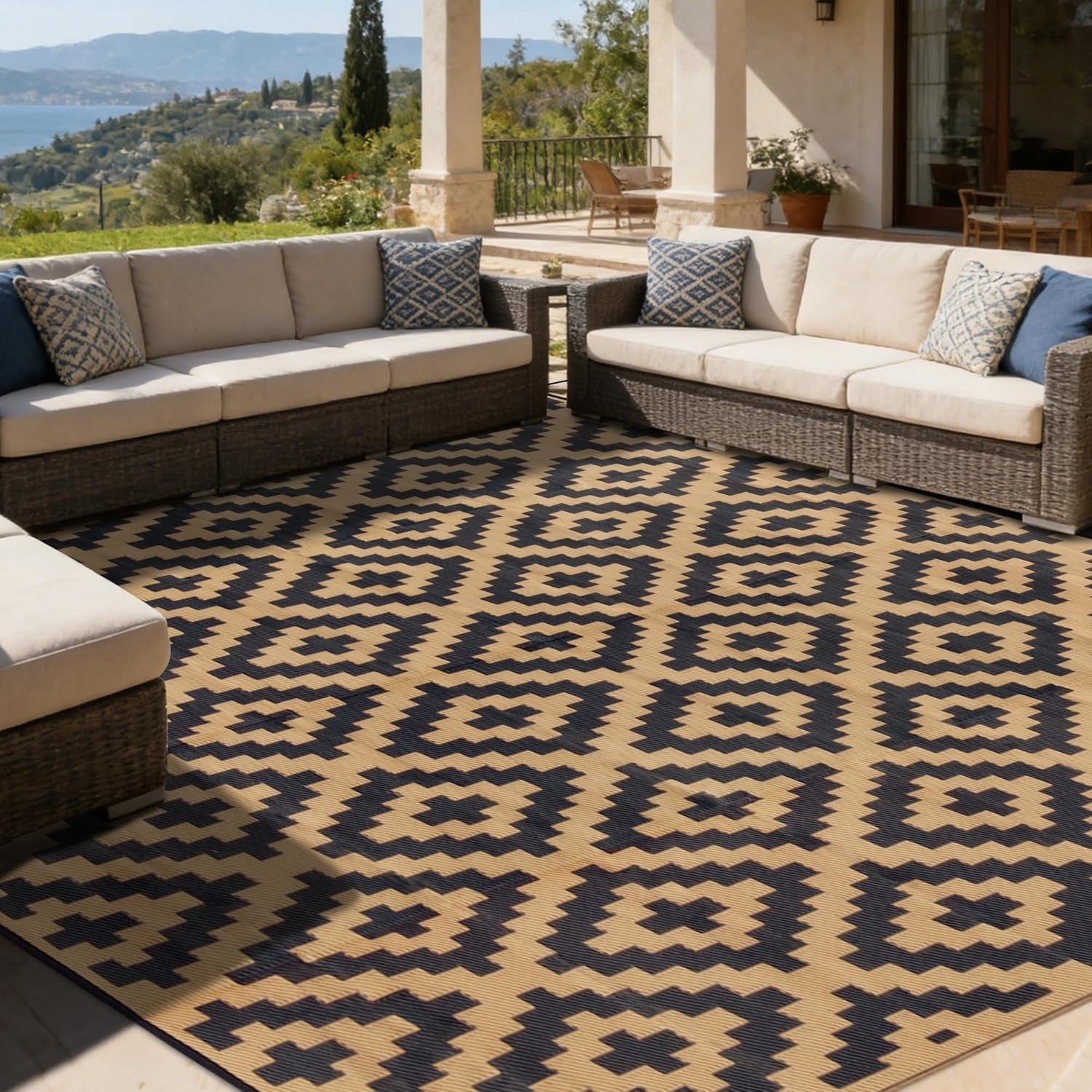 Large tan-and-black patterned outdoor rug filling a covered terrace with sectional seating.