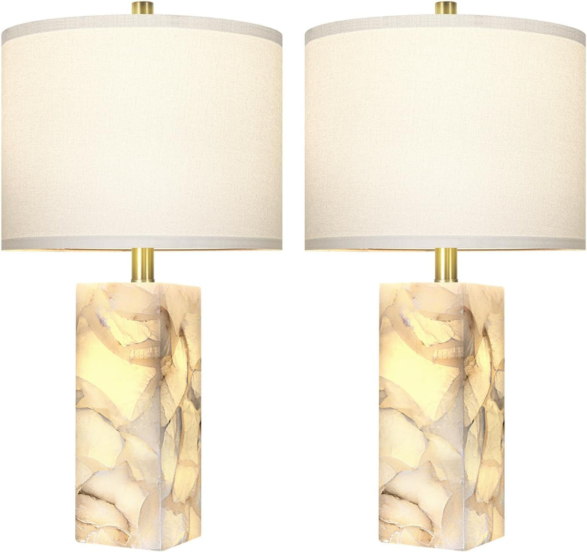 Two lamps lit against white, glowing alabaster bases visible through the stone with soft cream shades.