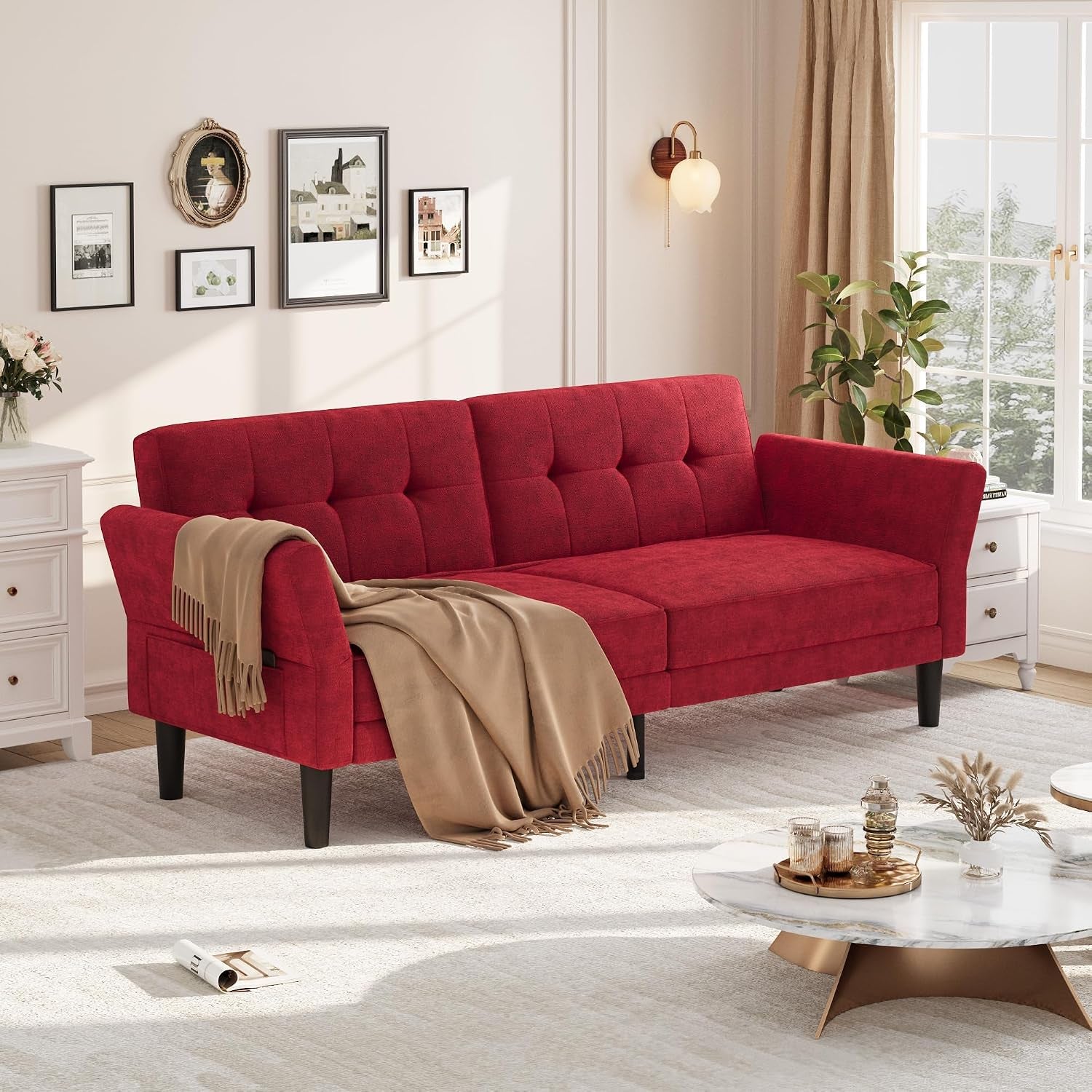Three-seat red chenille futon sofa with tufted back and beige throw in a sunlit living room.