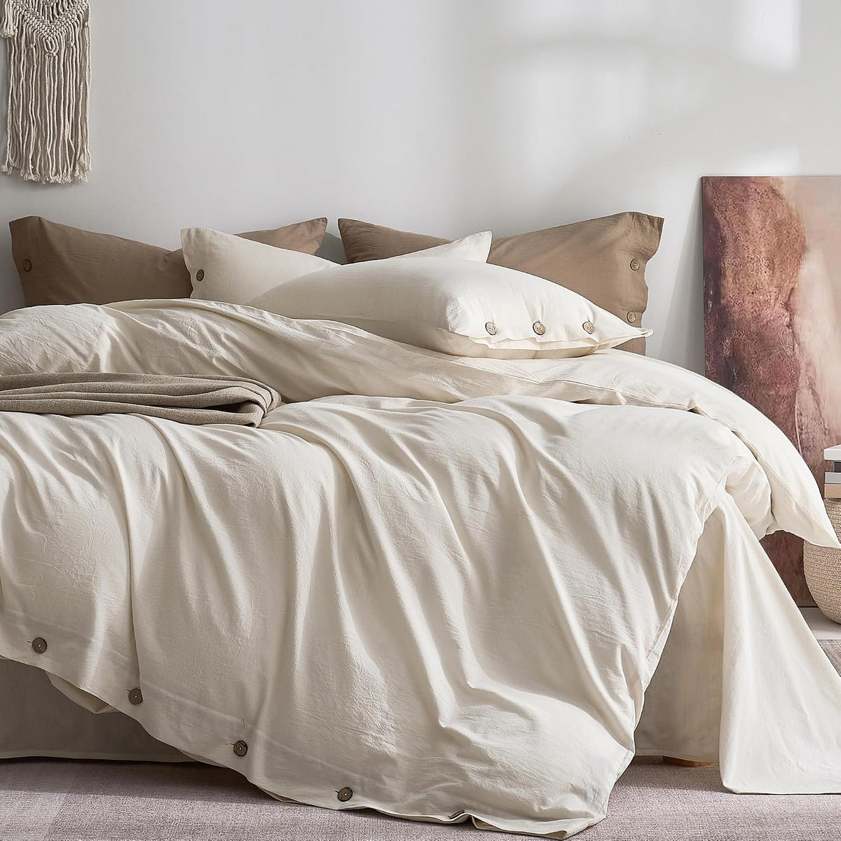 Full frontal bed view with soft cream duvet, folded throw and visible round wooden buttons along the edge.