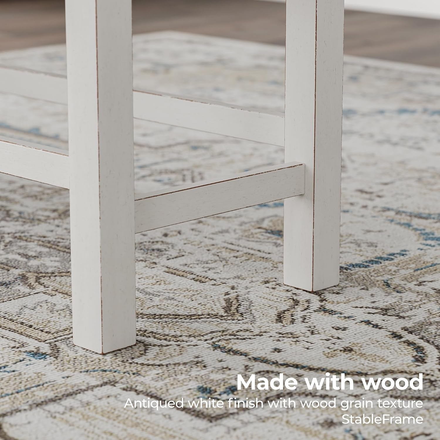 Close-up of antiqued white wood bench leg and stretcher showing distressed finish on patterned rug