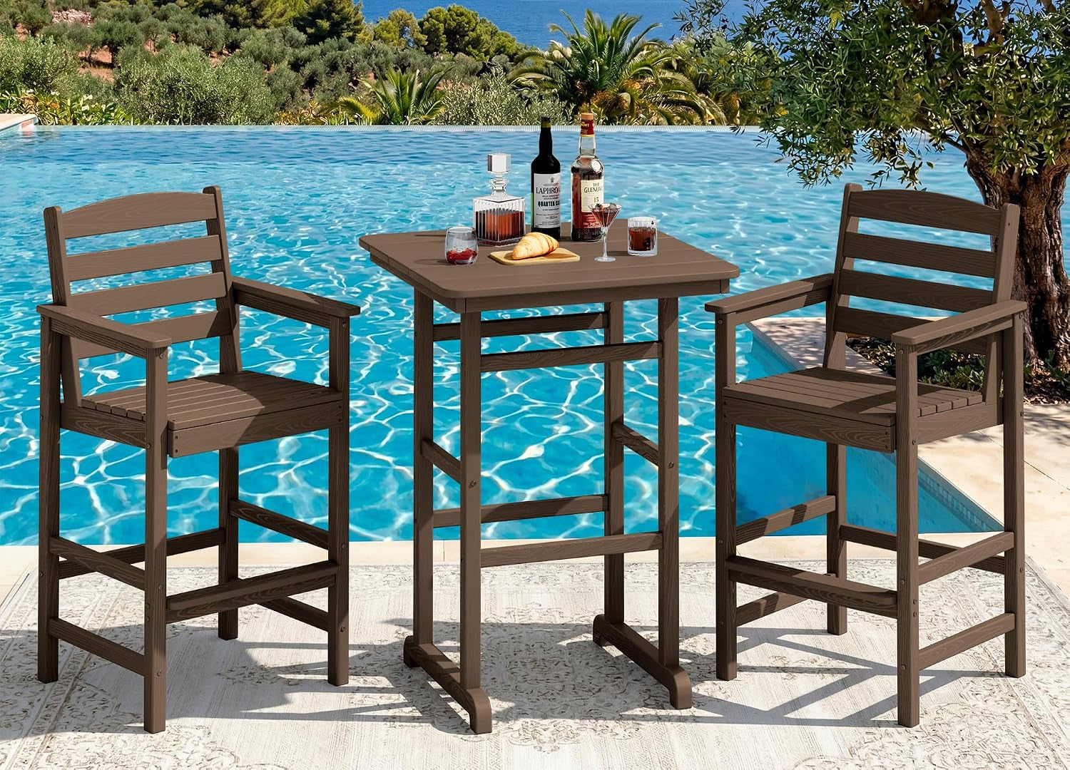 Brown bar-height pub table with two matching armchairs set beside a pool with drinks on the table