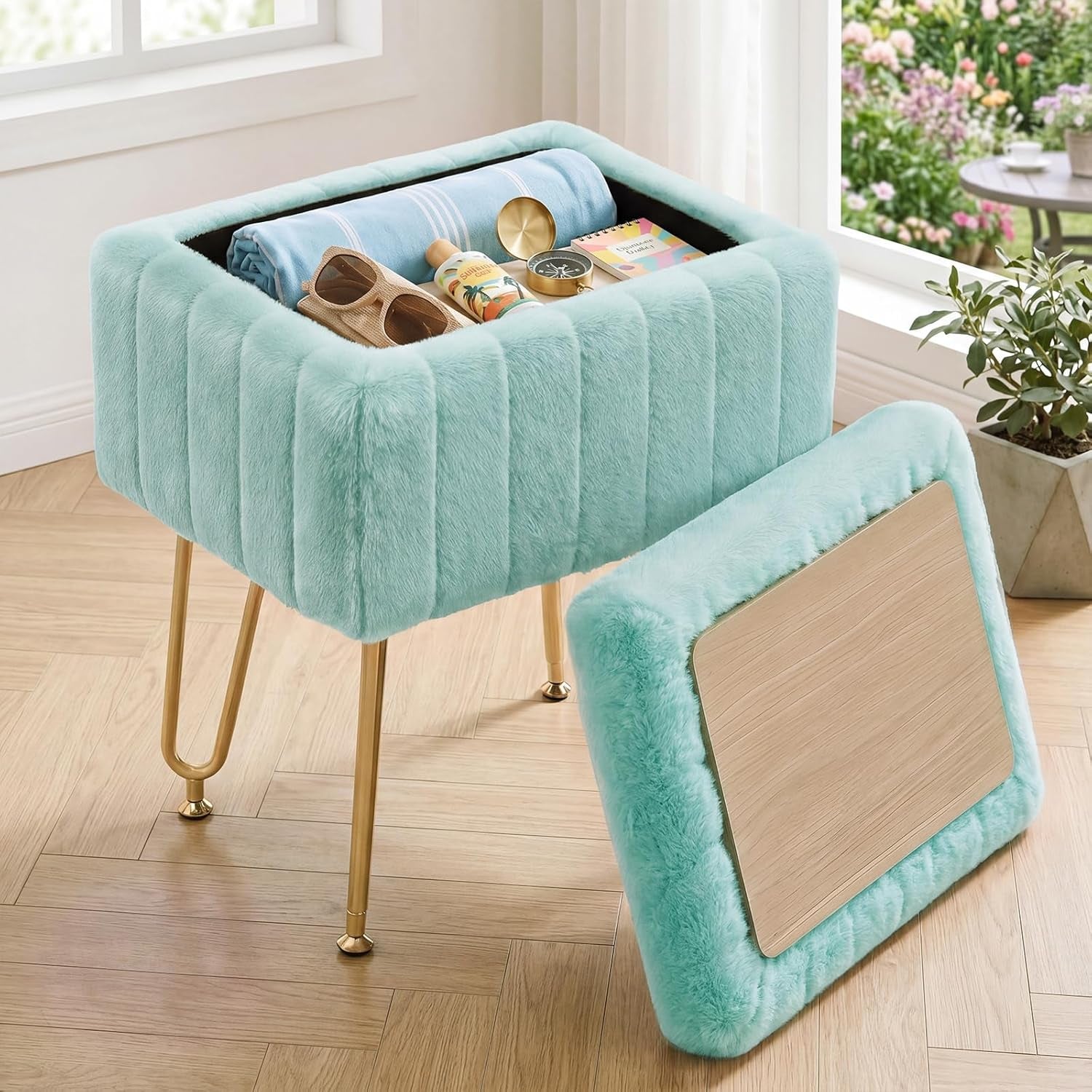 Mint faux-fur ottoman with lid removed revealing storage compartment and gold legs on wood floor.