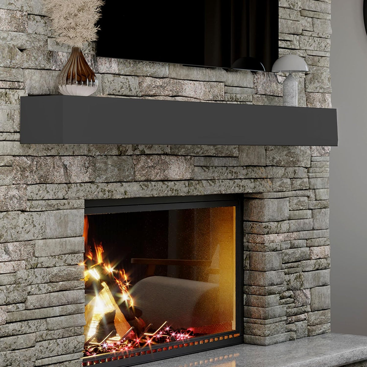 Black floating mantel centered on a stacked stone wall above a lit fireplace