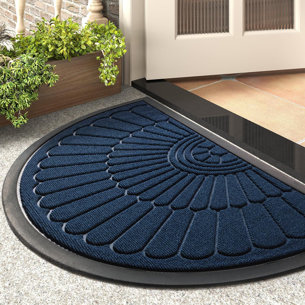 Low-angle close-up of a navy blue semicircular mat at an entry with a wooden planter beside it.