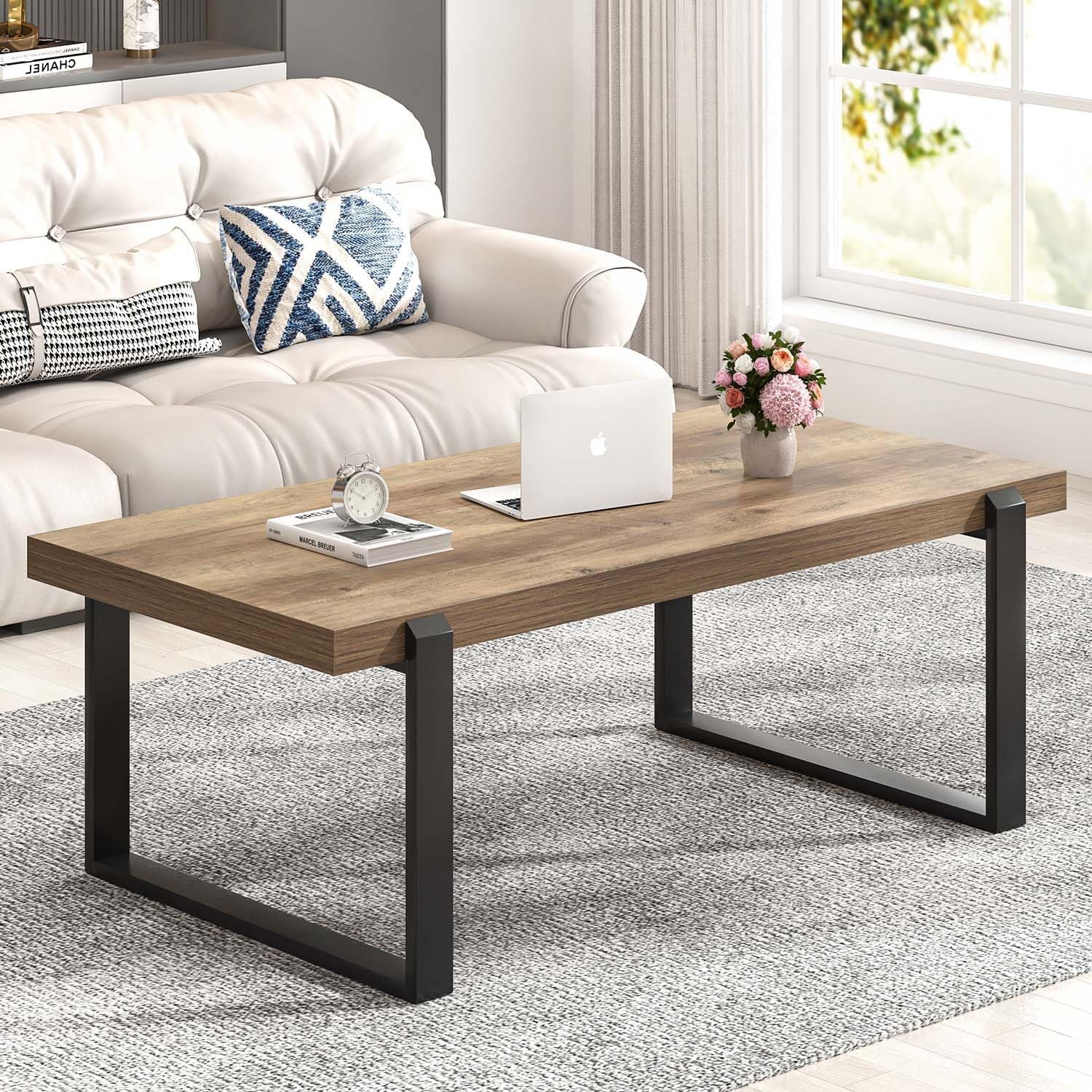 Warm rustic oak tabletop viewed from the front with black metal legs, styled with a laptop and vase of flowers.