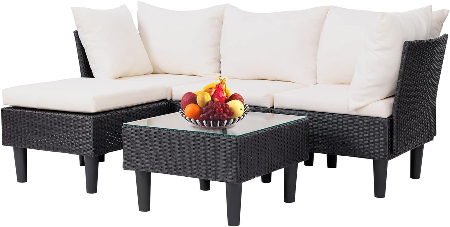 Dark rattan corner sofa with off-white cushions and matching ottoman beside a square glass-top coffee table