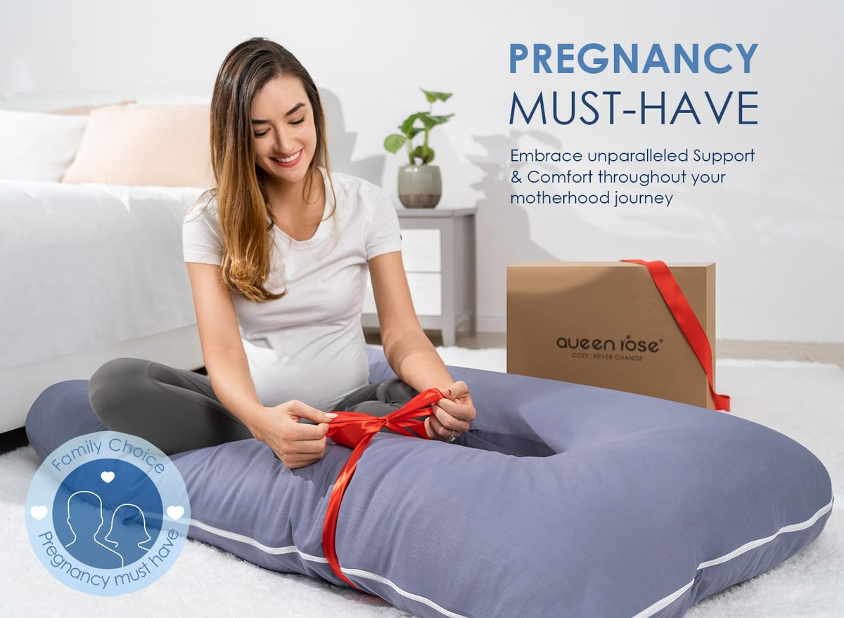 Pregnant woman sitting behind a blue U-shaped pillow tying a red ribbon, lifestyle shot on the floor