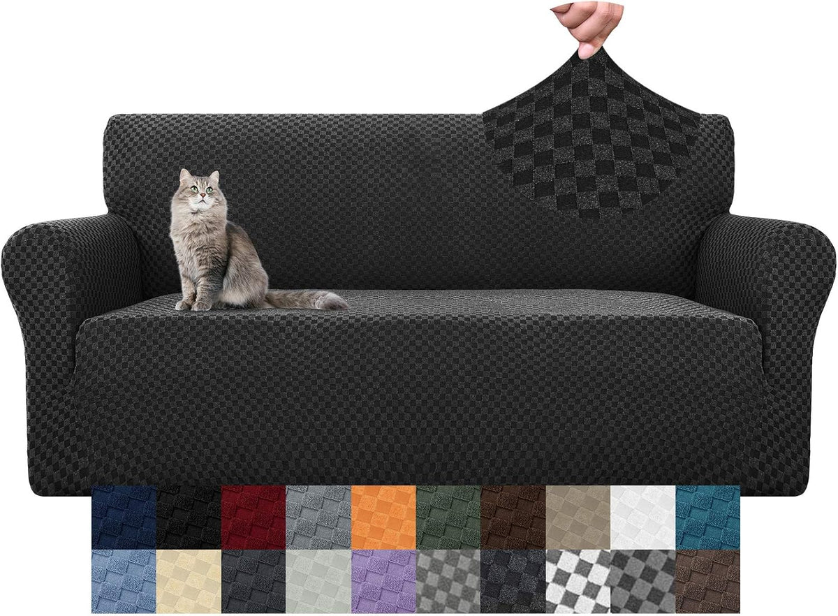 Charcoal textured stretch cover on a three-seat sofa with a gray cat on the cushion and a hand showing a fabric sample