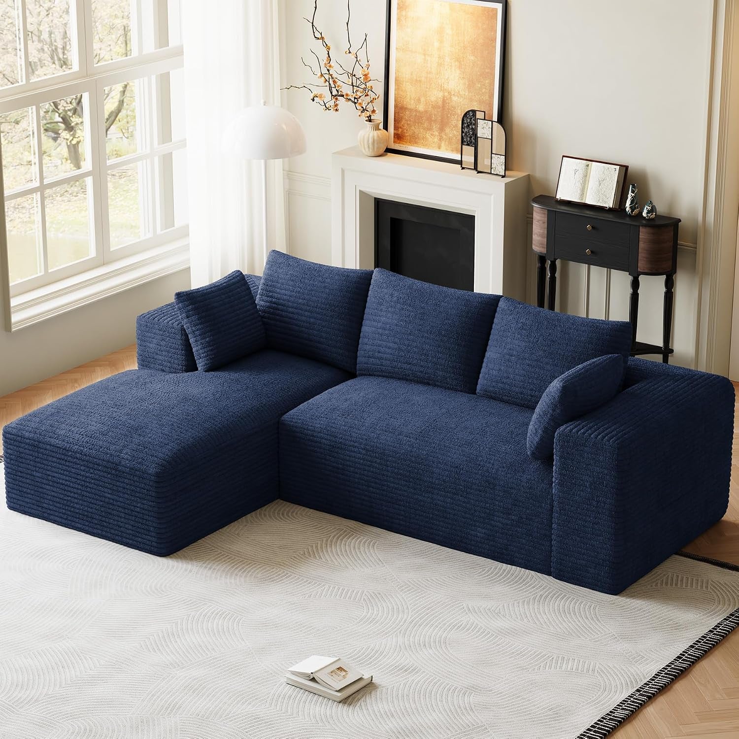 Navy blue L-shaped sectional with chaise shown in a sunlit room beside tall windows