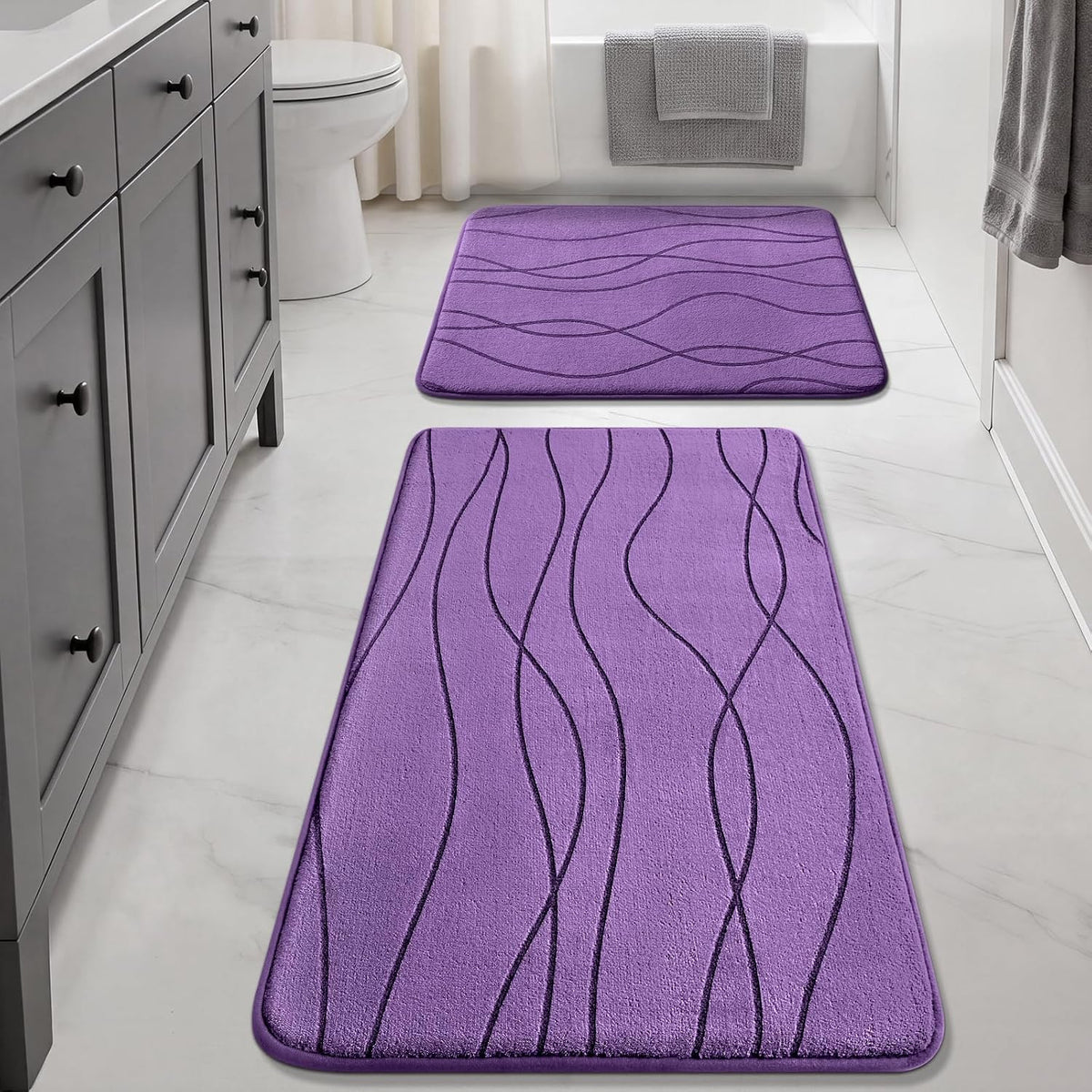 Long purple runner and square purple mat arranged in a light bathroom with vanity and tub