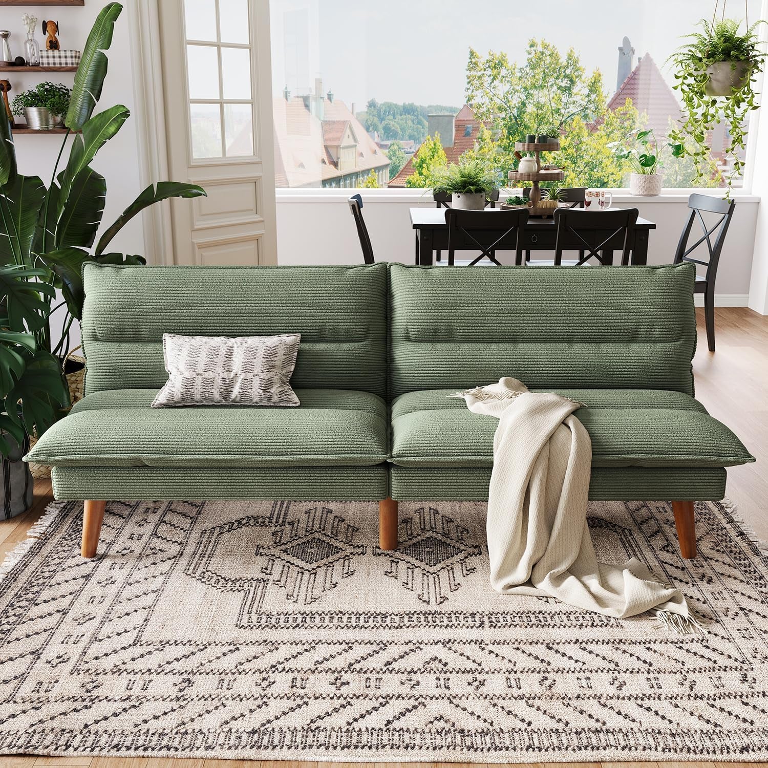 Front view of green corduroy futon sofa set against a bright dining-room backdrop