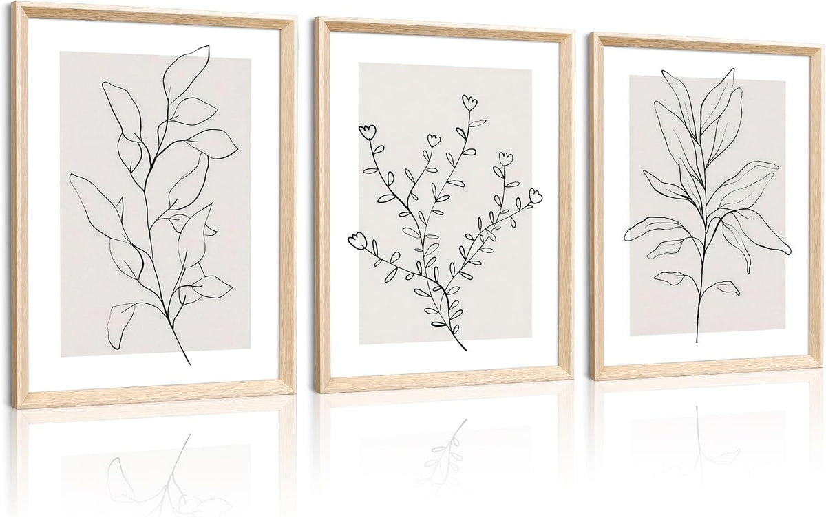 Triptych of vertical framed botanical line drawings in pale wood frames, shown side by side with subtle reflections below.