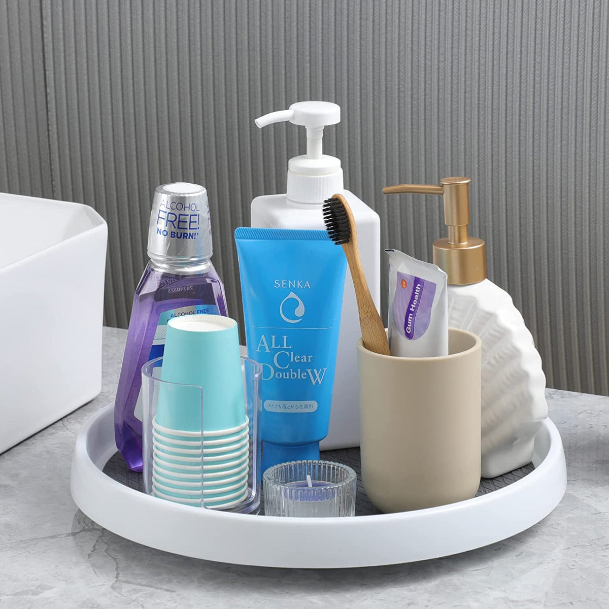 Bathroom counter close-up with a single white turntable holding toiletries and cups.