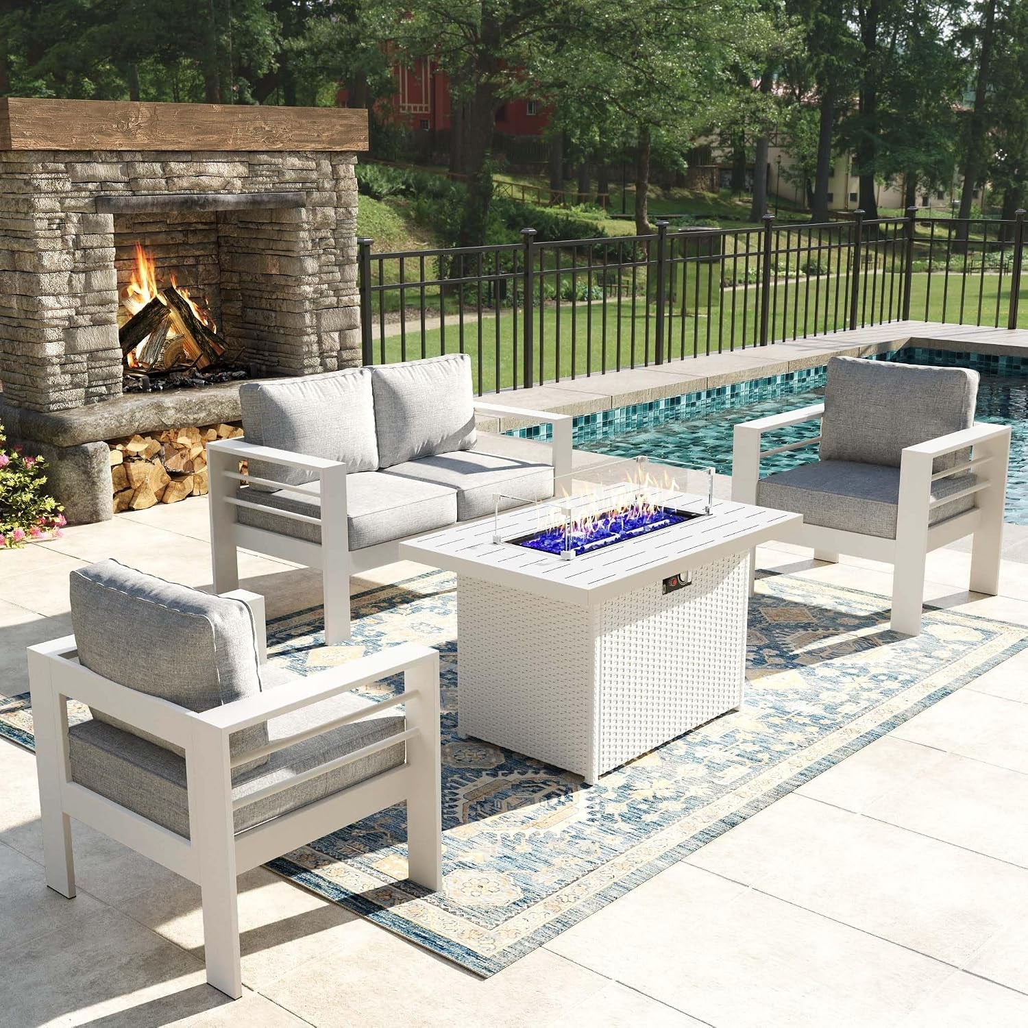 White outdoor seating set with light gray cushions and a square fire table on a patterned rug.