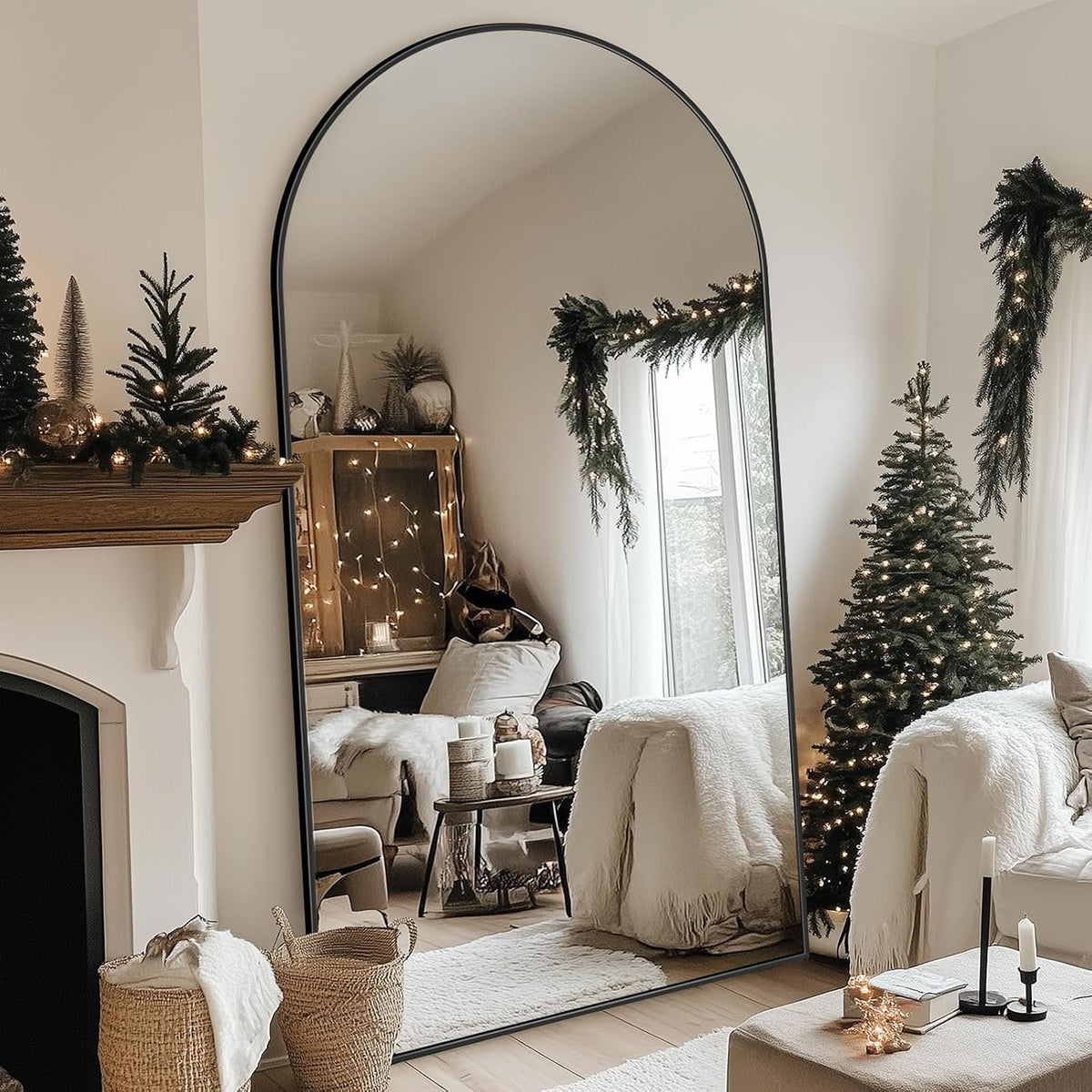 Tall arched full-length mirror with dark frame leaning against a living room wall beside holiday decor