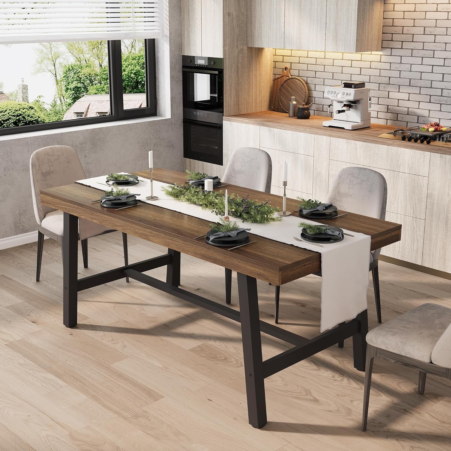 Warm brown wood-top rectangular table with black metal legs decorated with candles and greenery in a kitchen.