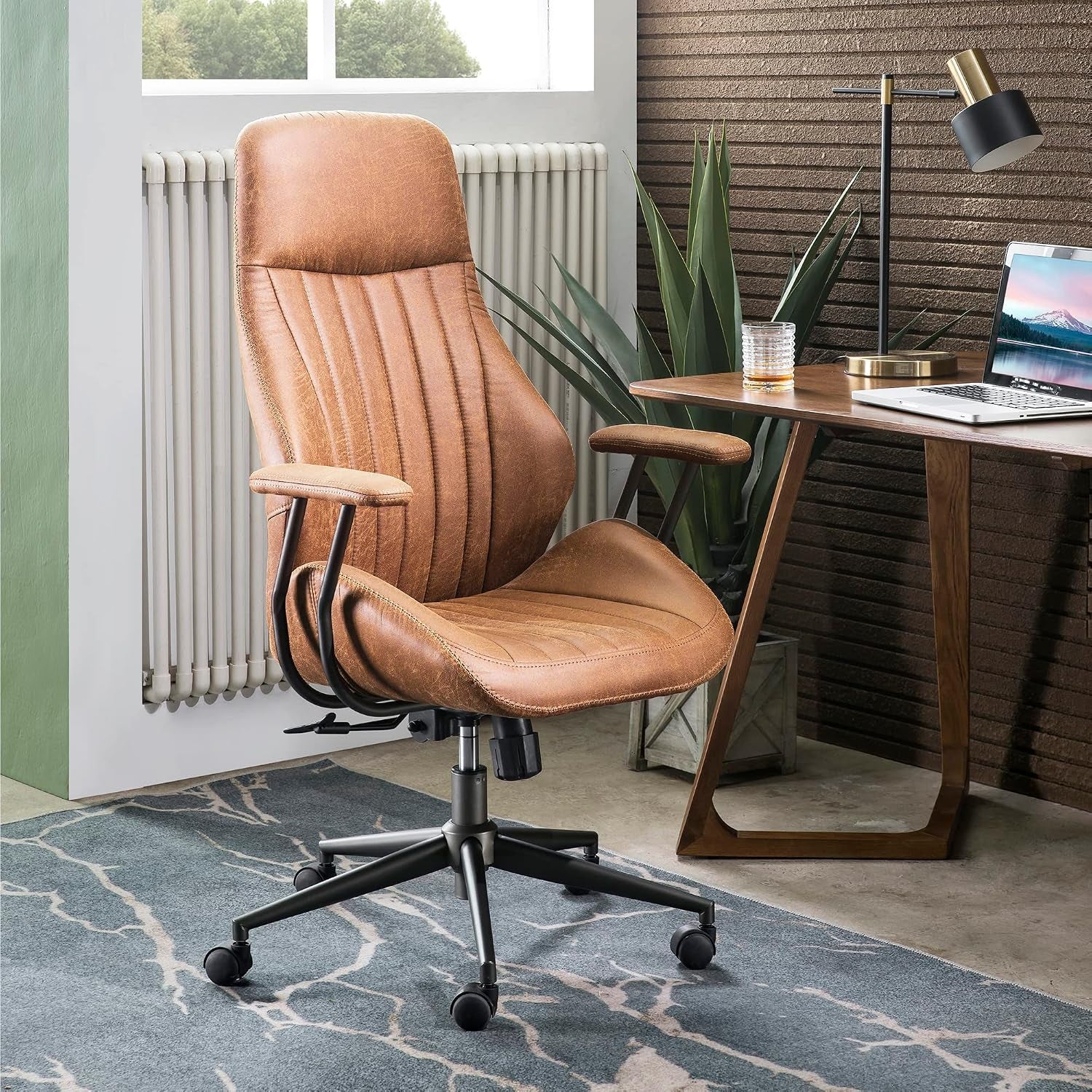 Brown faux suede high-back office chair placed beside a wood desk in a styled home office setting