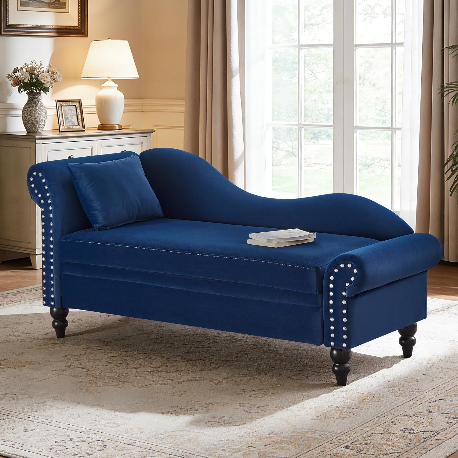 Right-facing blue upholstered chaise with rolled arms, silver nailhead trim, turned dark legs and a matching throw pillow