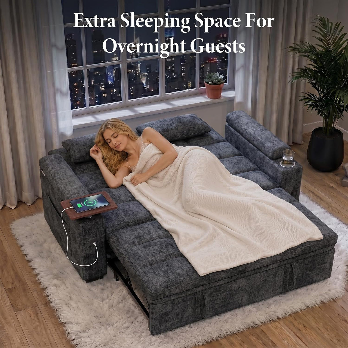 Overhead view of the charcoal sofa converted to a bed with a woman sleeping under a blanket and a swivel table at the side.