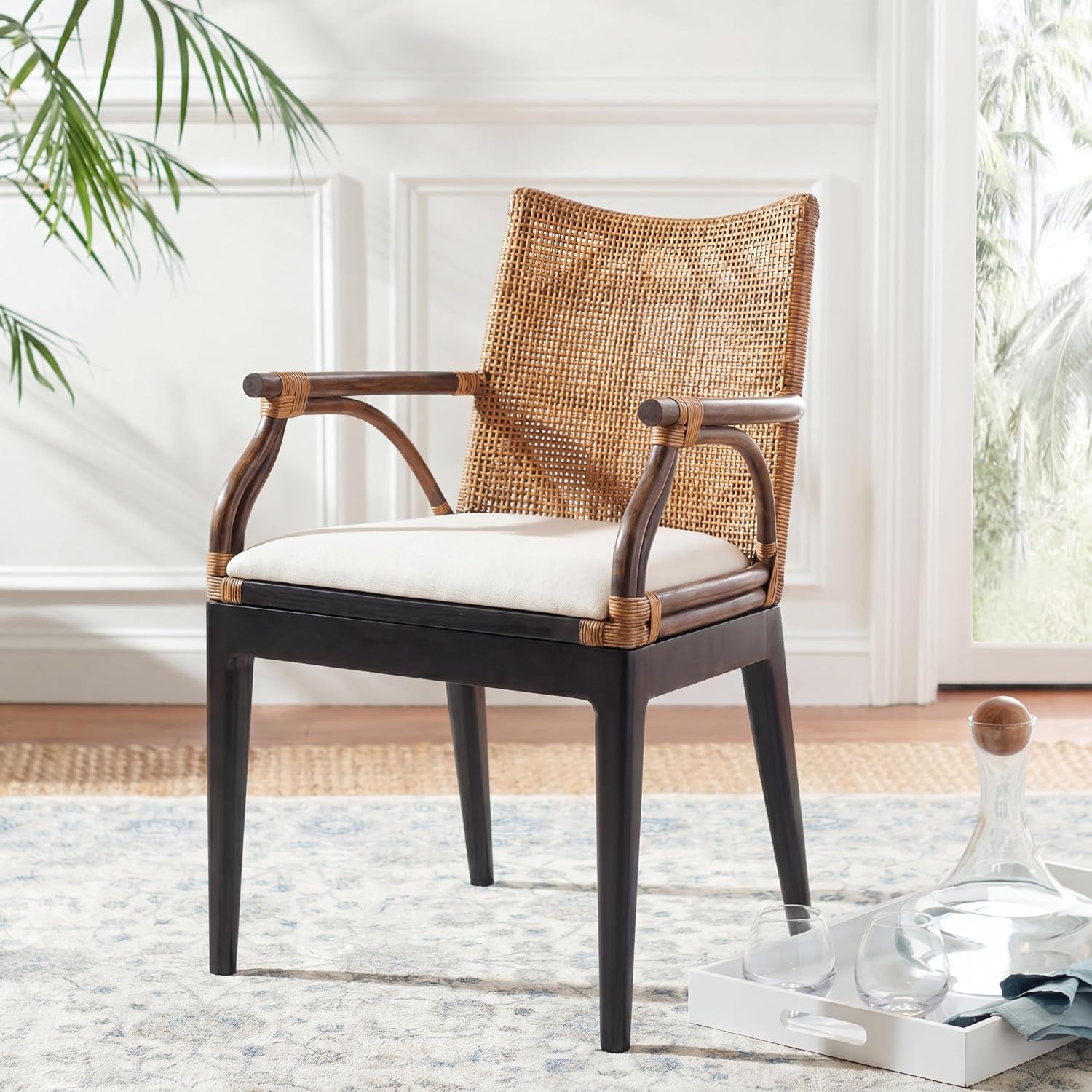Rattan arm chair placed on a patterned rug near a window showing full side angle