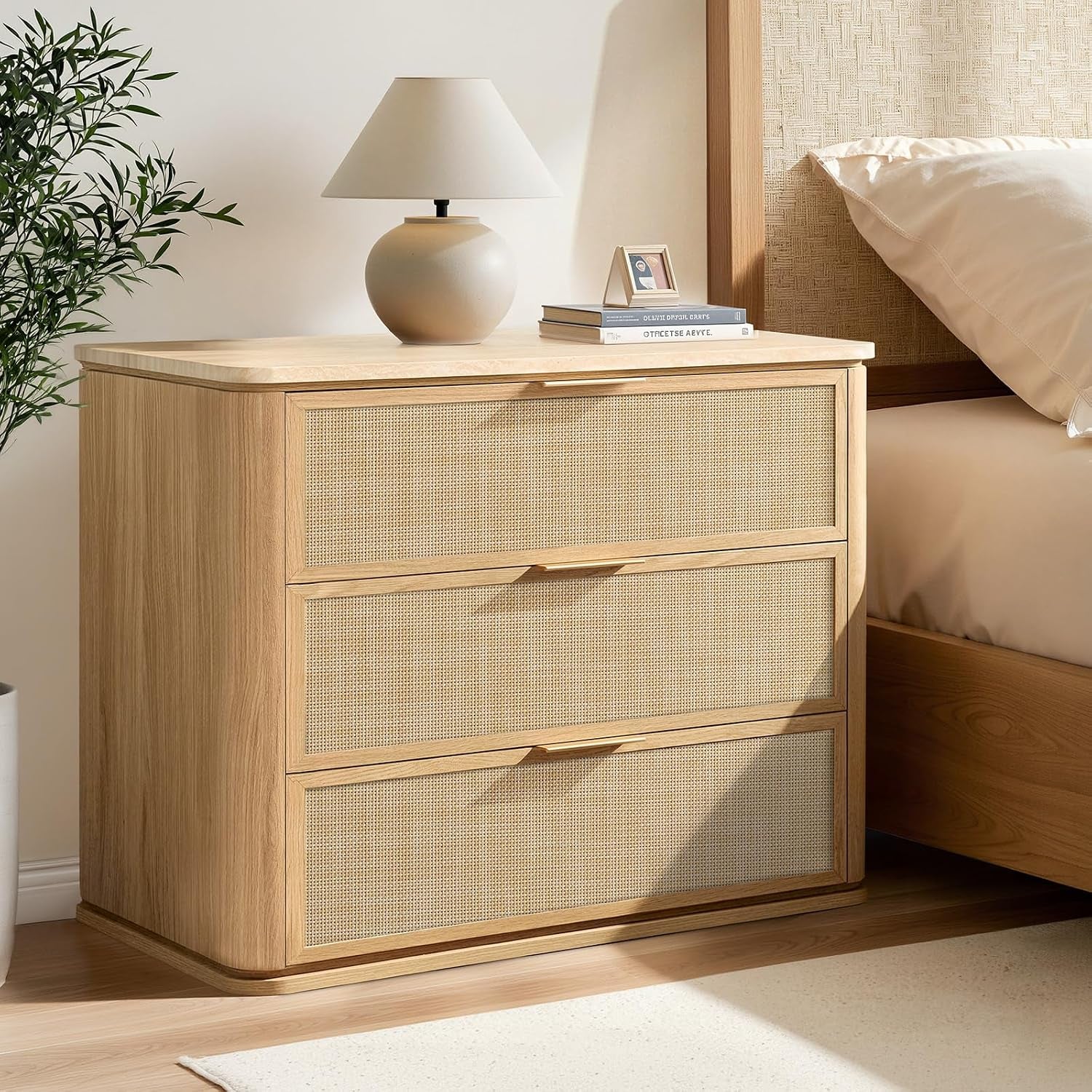 Light oak three-drawer nightstand with woven fronts next to a bed, faux marble top with lamp.