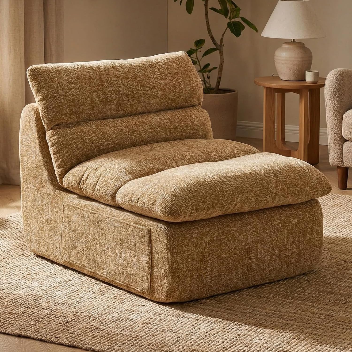 Front-left lifestyle view of the boneless floor chair in warm tan chenille on a woven rug beside a wooden side table and