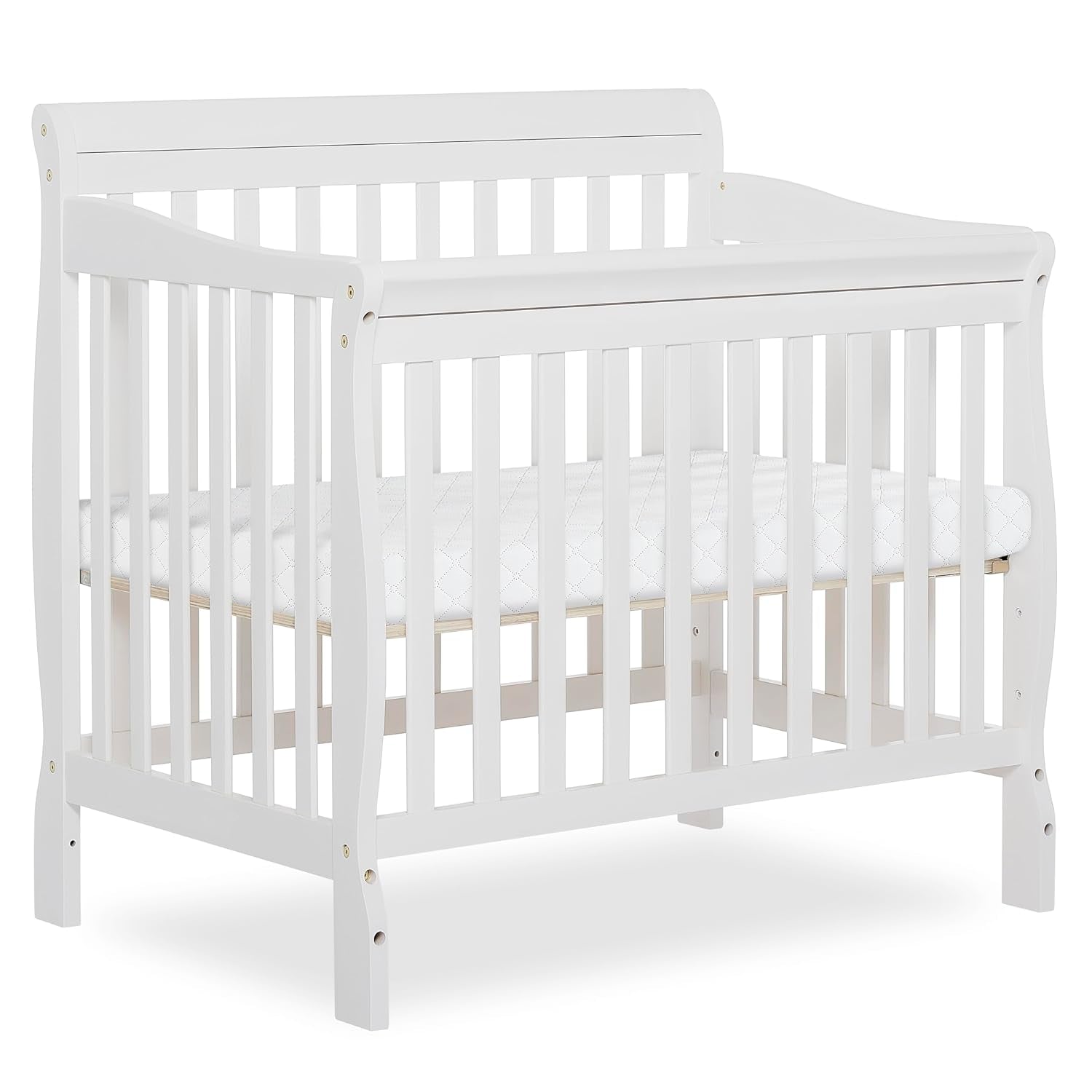 Front three-quarter view of a small white wooden baby crib with mattress on a plain background