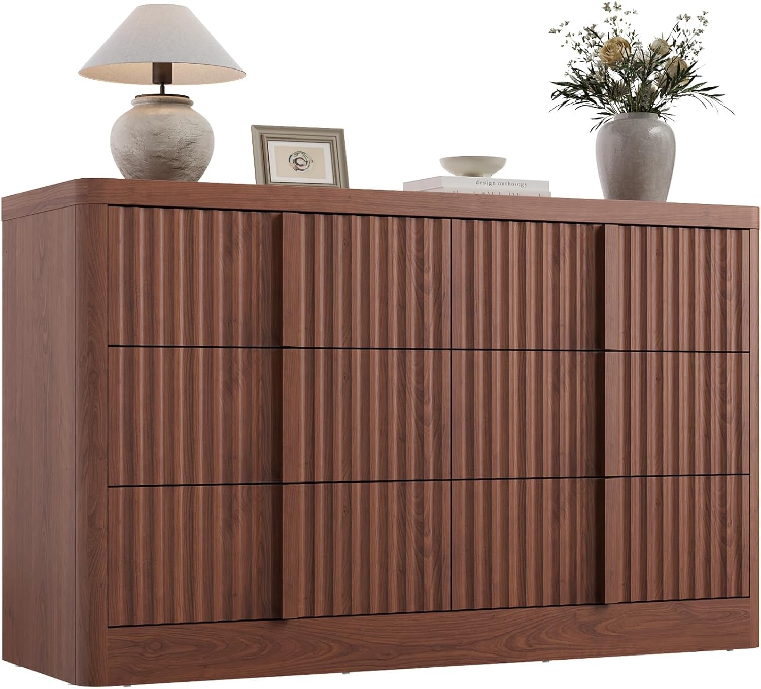 Six-drawer dresser with vertical fluted fronts in a warm walnut finish, topped with a lamp and floral vase.