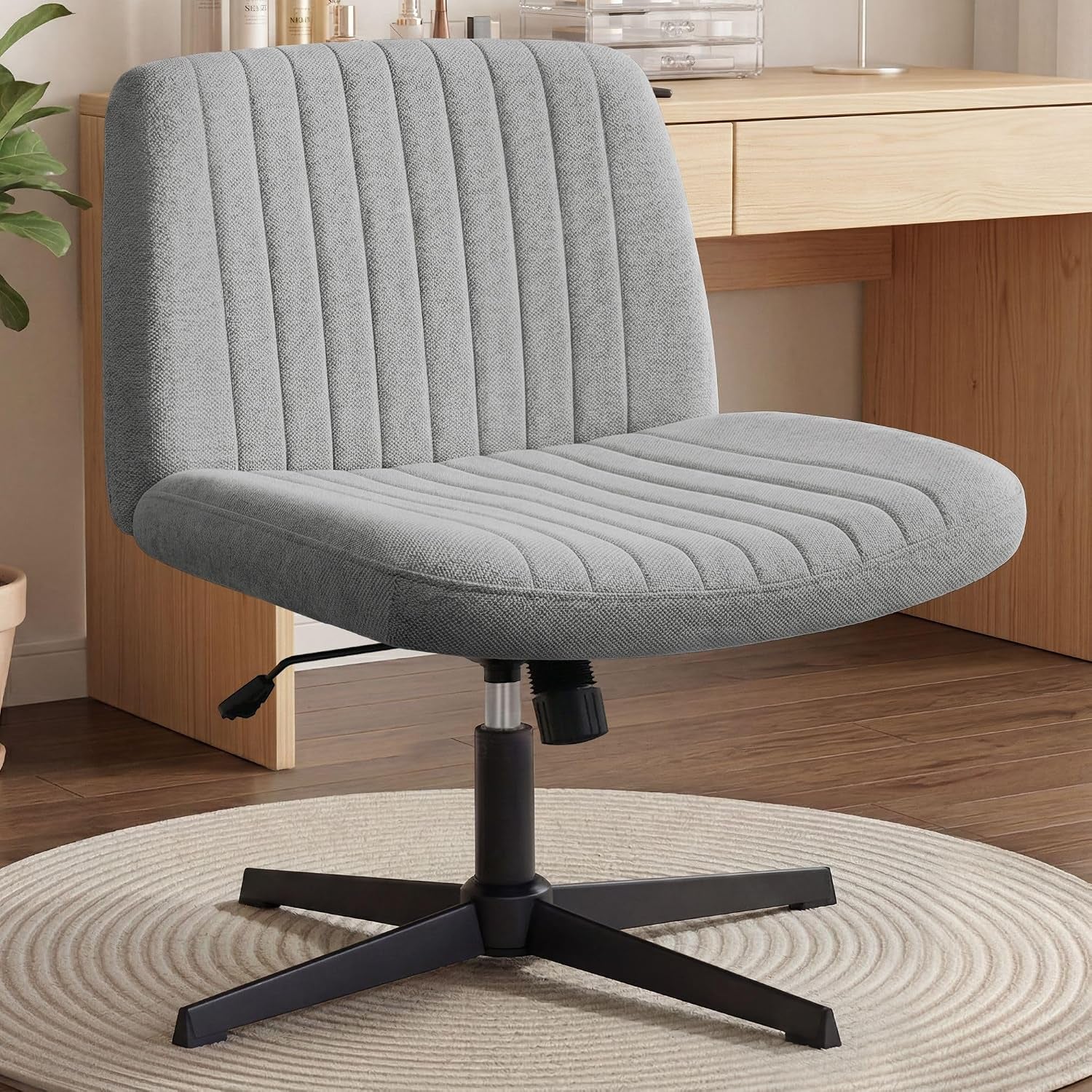 Styled desk scene close-up of a mid-gray fabric swivel chair beside a light wood desk on a round rug.