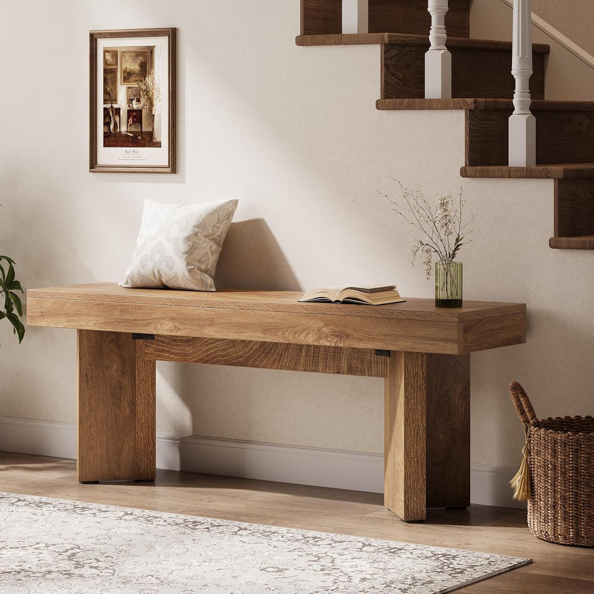 Rustic brown bench positioned under a staircase with a vase and book styled on its surface