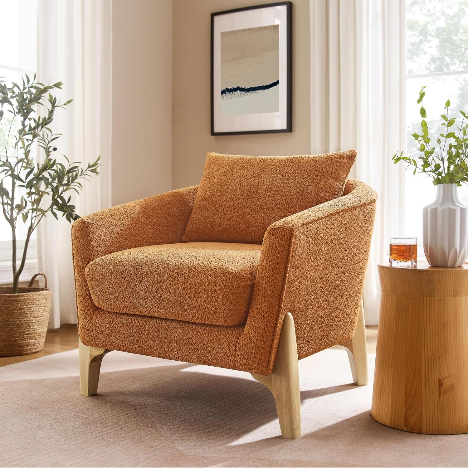 Single burnt orange oversized fleece accent chair with sculpted light wood legs beside a round wood side table.