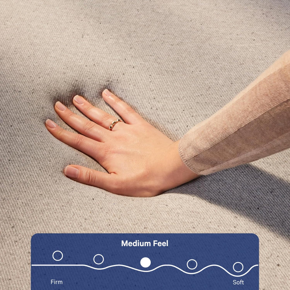 Close-up of a hand pressing into the gray mattress cover to show responsive foam indentation.