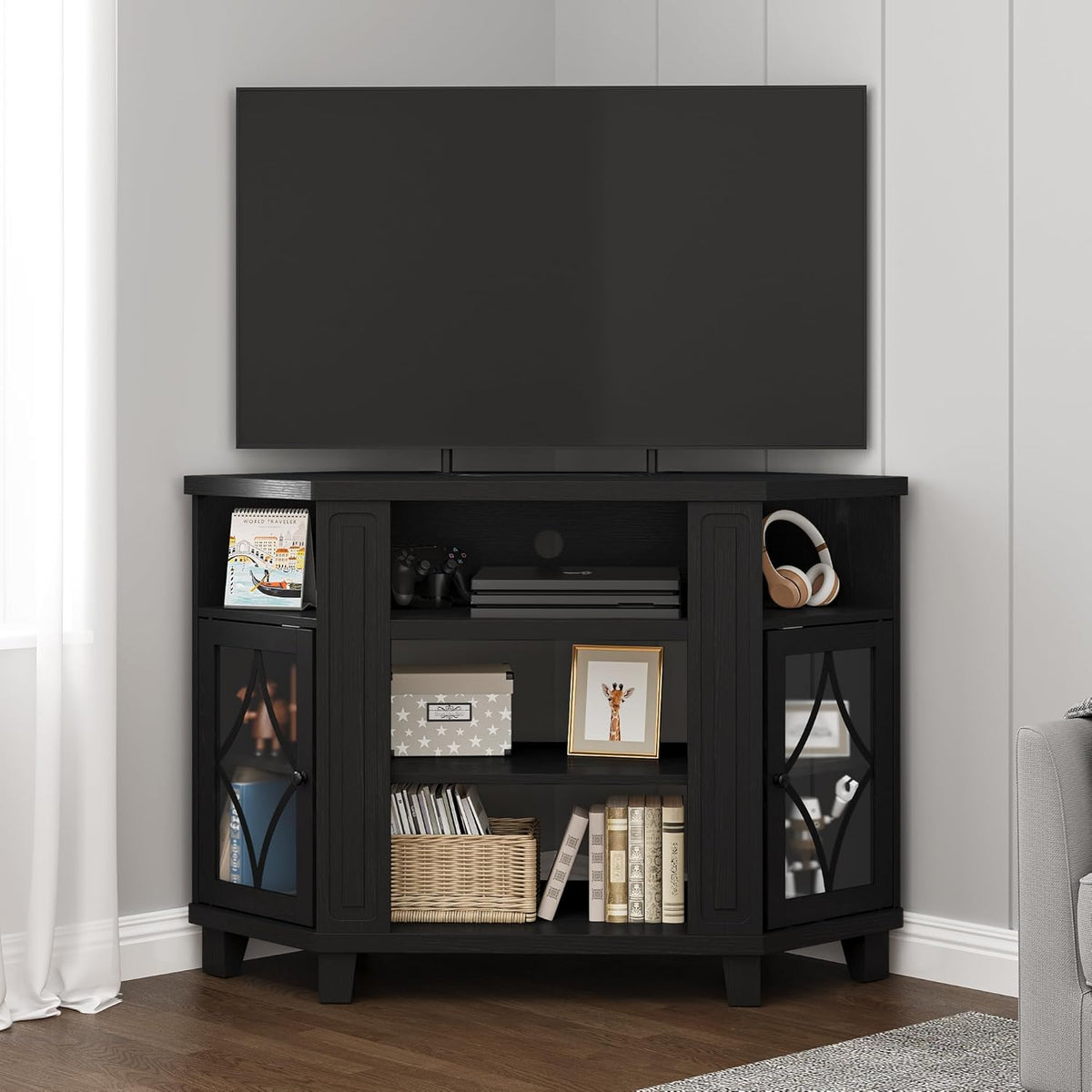 Corner scene of the same stand in black finish with headphones, game controller and decorative basket.