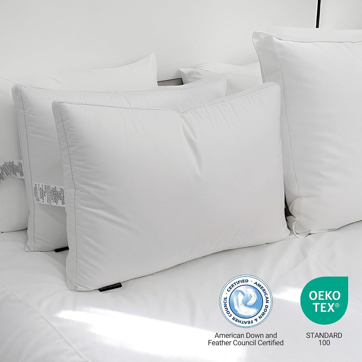 Three plump white pillows arranged on a bed with certification logos at the lower corner.