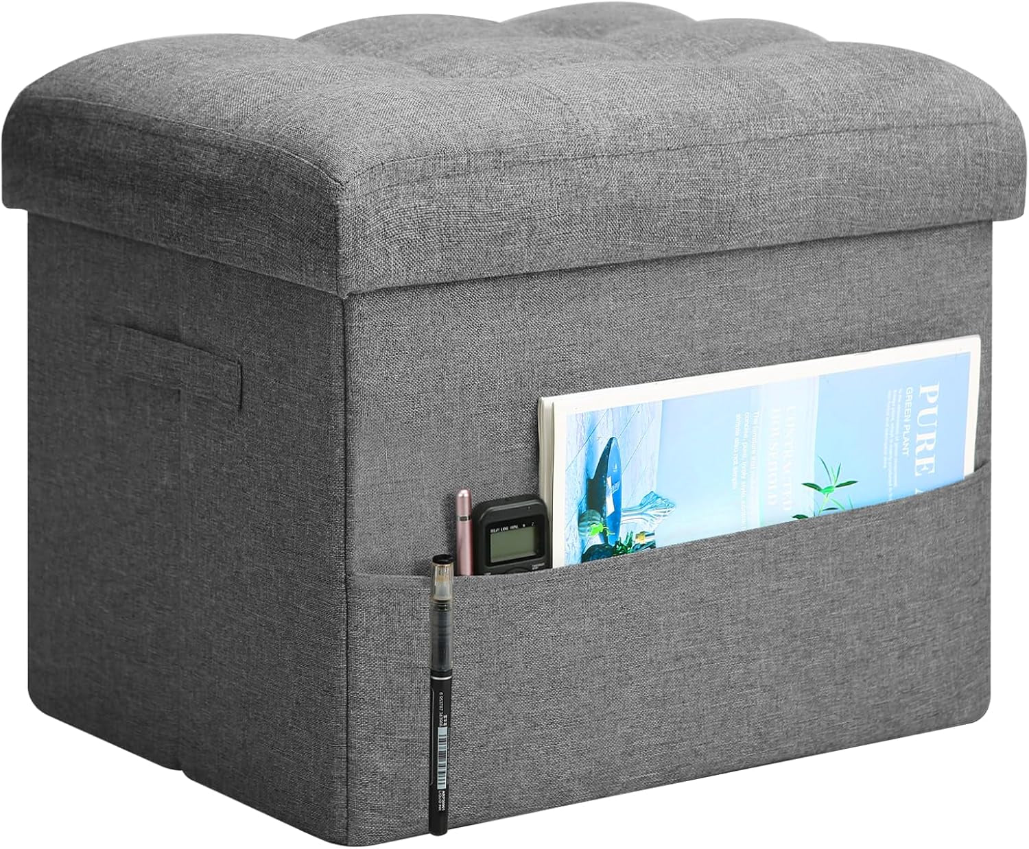 Dark gray tufted storage ottoman front corner view showing side pocket with magazine and pens