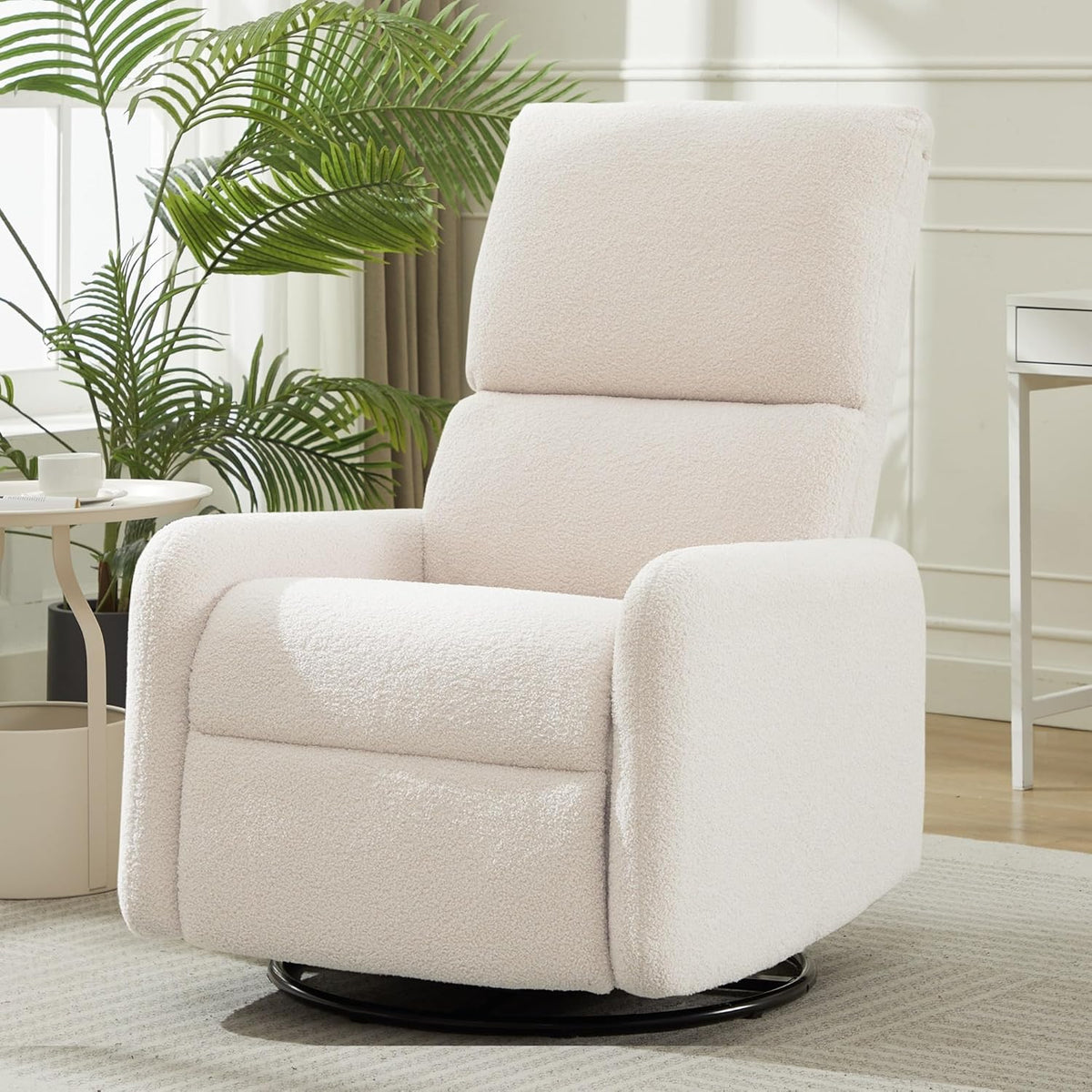 Front three-quarter view of a cream sherpa swivel rocker chair on a round black base in a bright living room.