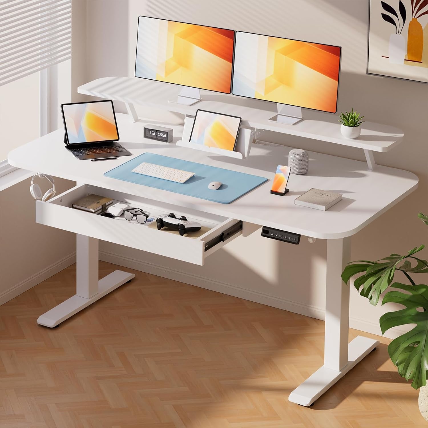 Angled view of the white desk in a bright room with dual monitors, blue mousepad and the drawer partially open