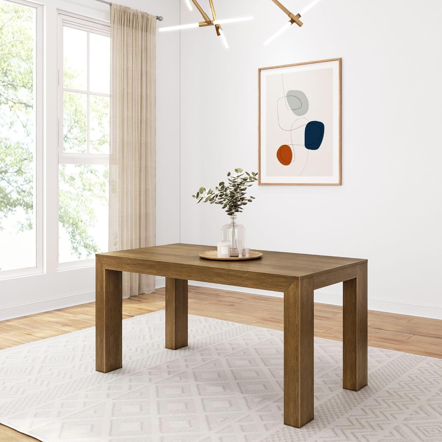 Darker wood rectangular dining table on a light patterned rug with framed art and pendant light