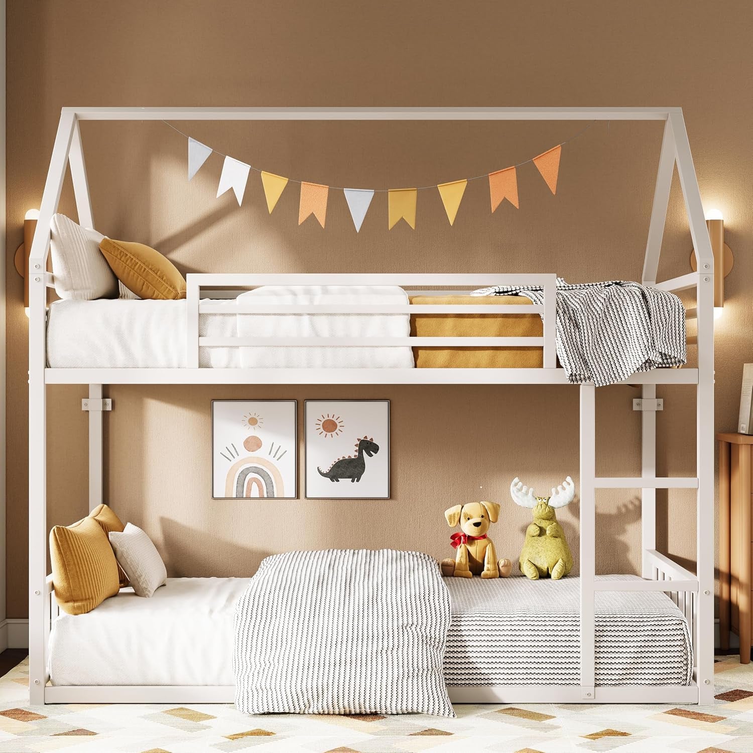 Front view of a white house‑frame twin over twin bunk bed in a warm bedroom, with pillows, bunting and stuffed toys.