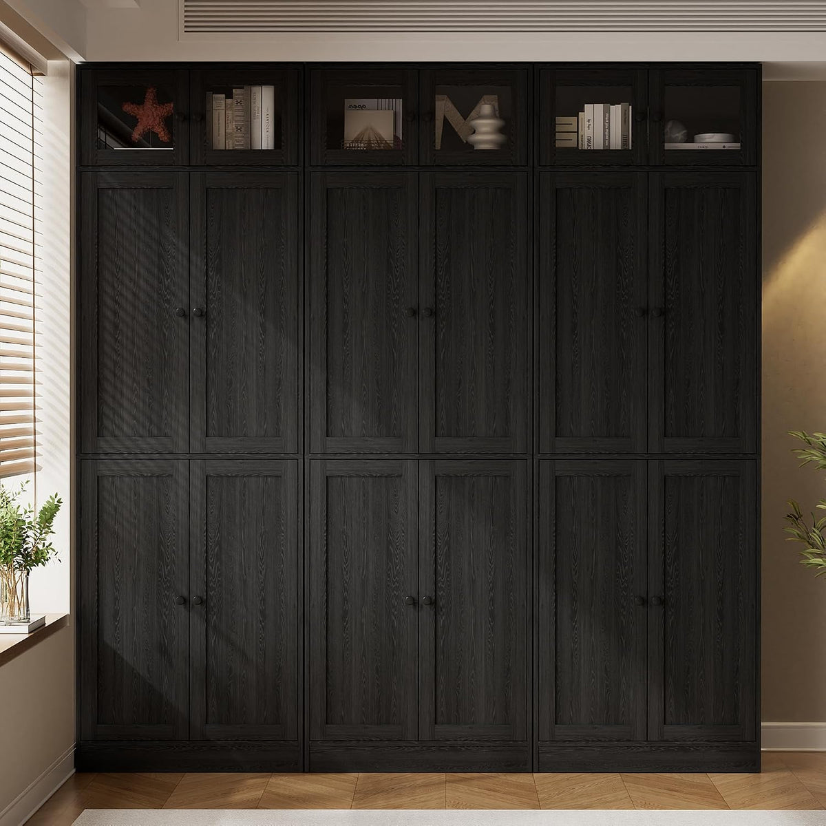 Front view of three black bookcase modules with small round knobs and paneled lower doors.