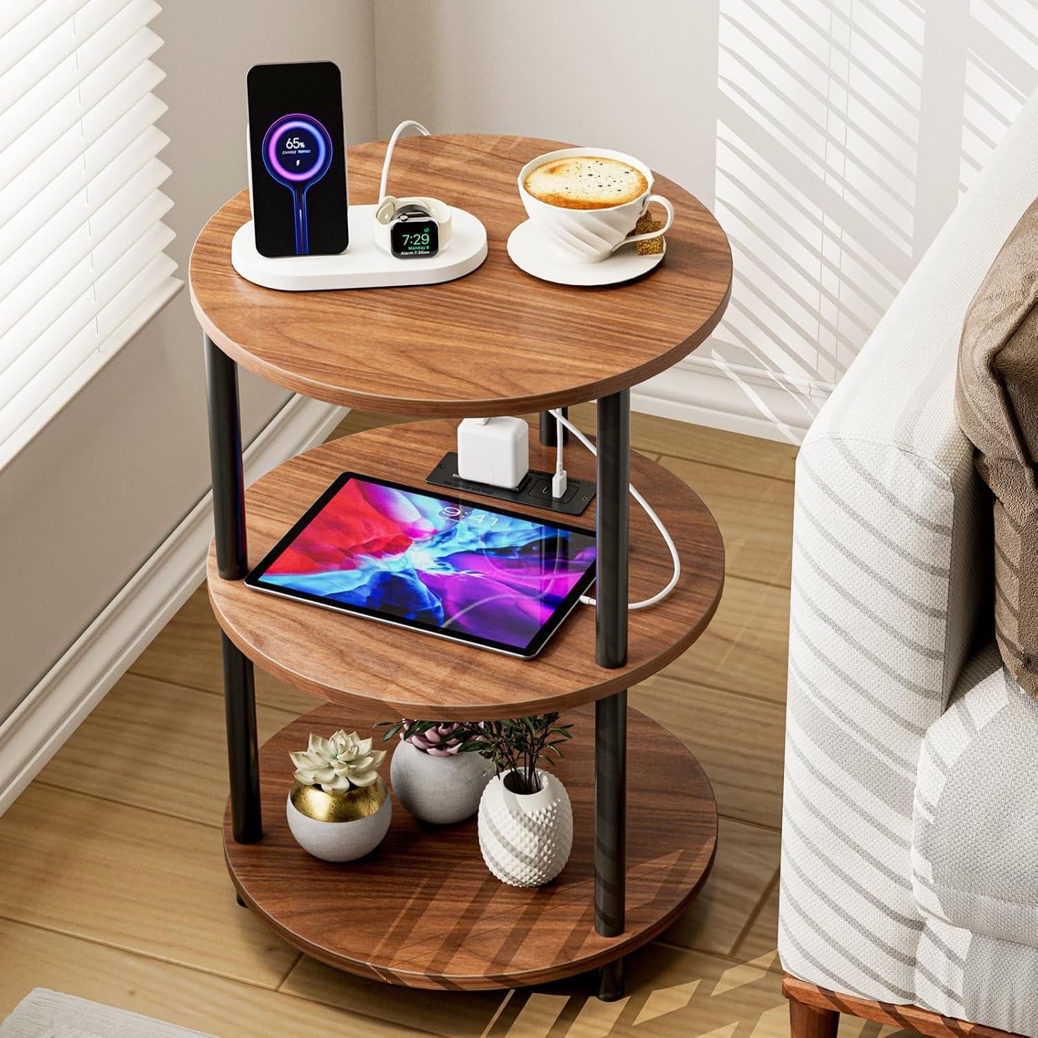 Close top-down view of the round three-tier table with electronics and a coffee cup on top.